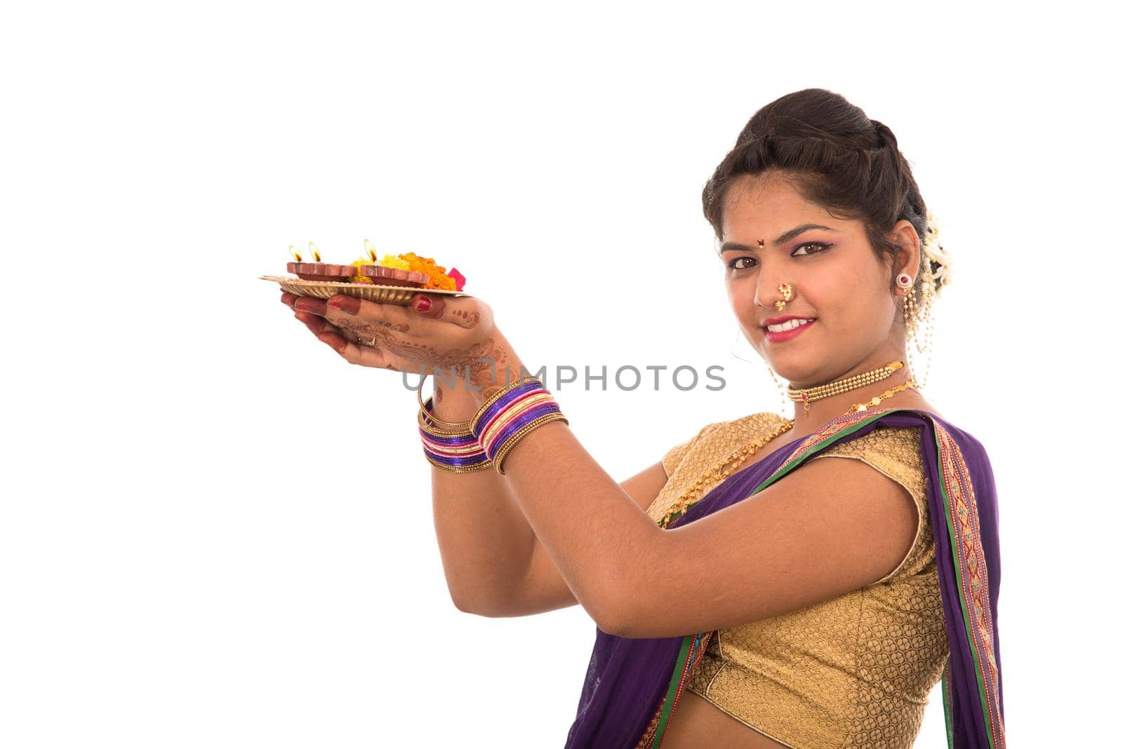 Portrait of a Indian Traditional Girl holding pooja thali with diya during festival of light on white background. Diwali or deepavali