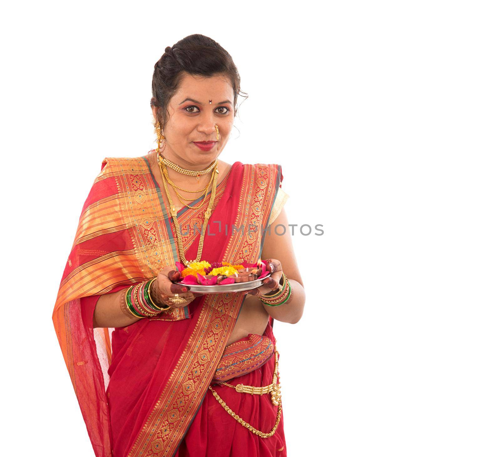 Portrait of a Indian Traditional Girl holding pooja thali with diya during festival of light on white background. Diwali or deepavali