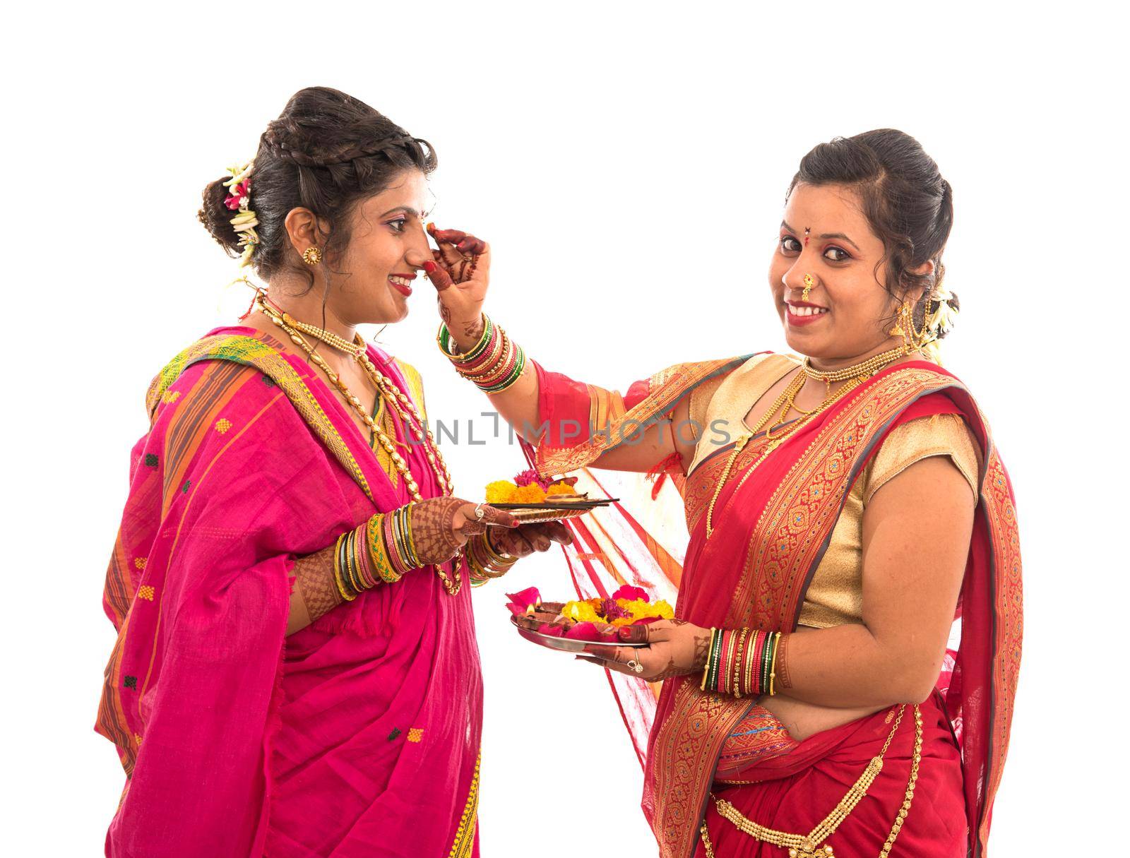 Portrait of Indian Traditional Girls holding diya and flower thali, Sisters celebrating Diwali or deepavali holding oil lamp during festival on white background