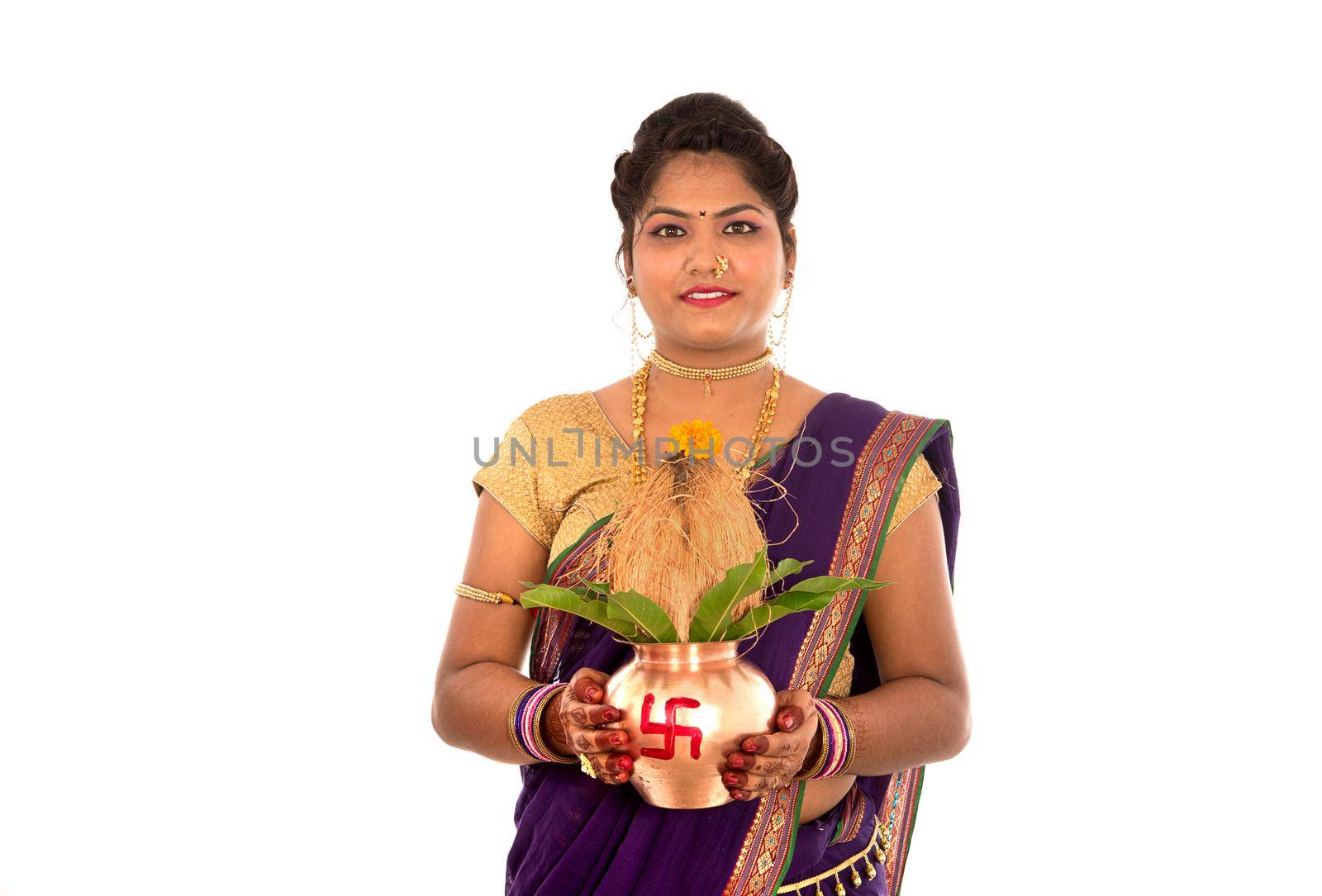 Indian Traditional Woman holding a traditional copper kalash, Indian Festival, copper kalash with coconut and mango leaf with floral decoration, essential in hindu puja.