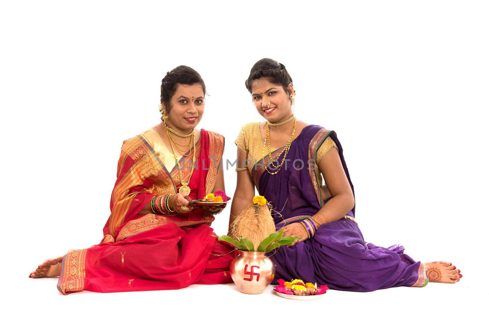 Indian Traditional Sisters performing worship, Indian Festival, copper kalash with coconut and mango leaf with floral decoration, essential in hindu puja.