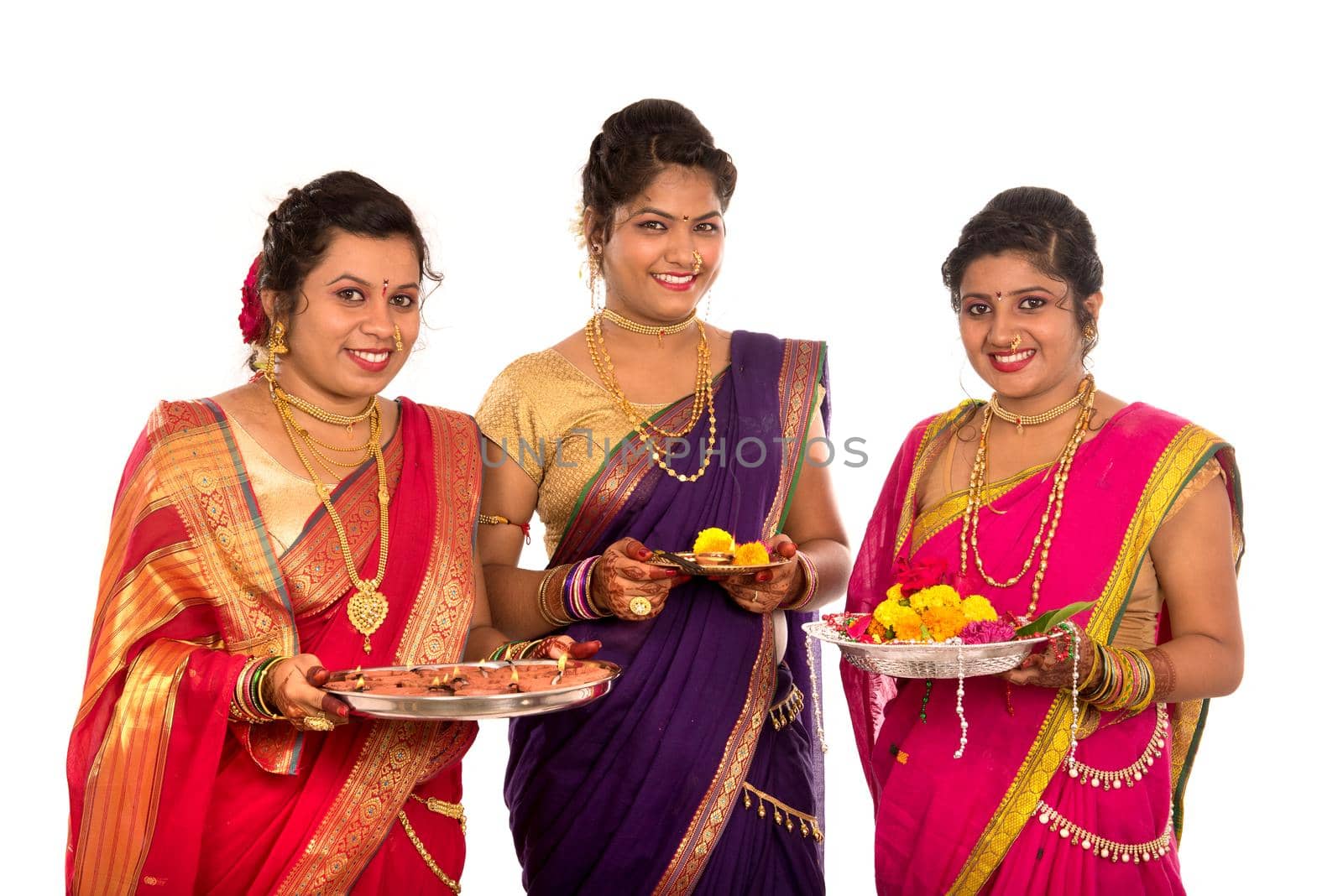 Portrait of Indian Traditional Girls holding diya and flower thali, Sisters celebrating Diwali or deepavali holding oil lamp during festival on white background