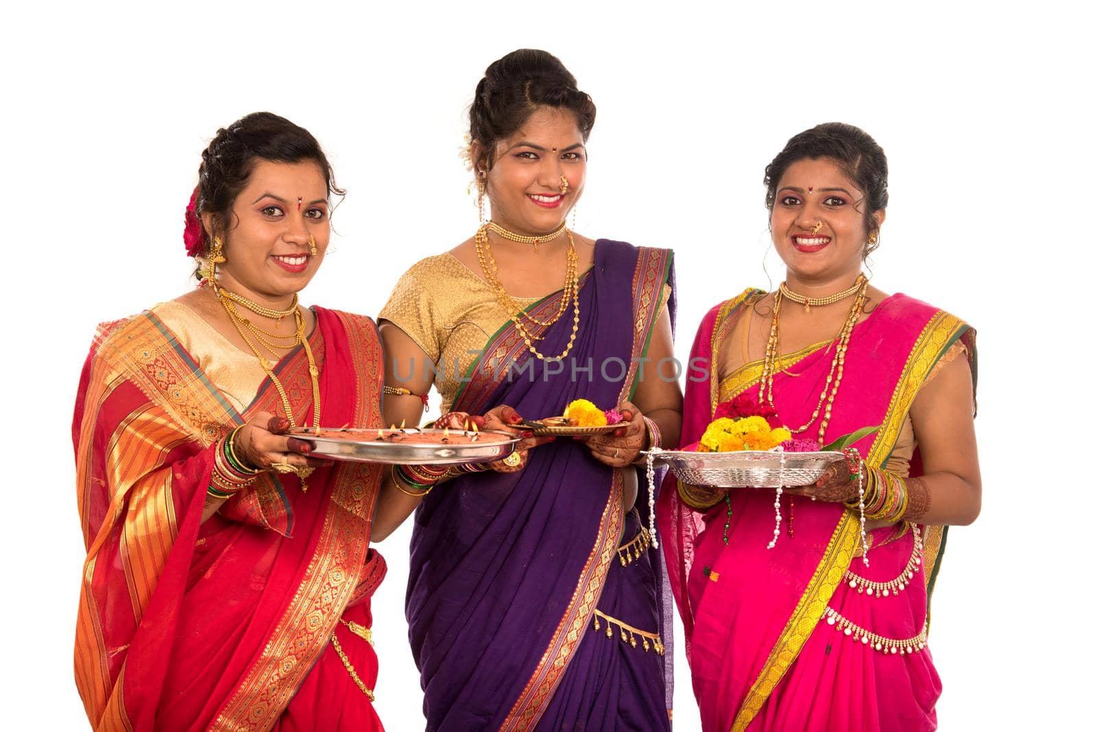 Portrait of Indian Traditional Girls holding diya and flower thali, Sisters celebrating Diwali or deepavali holding oil lamp during festival on white background