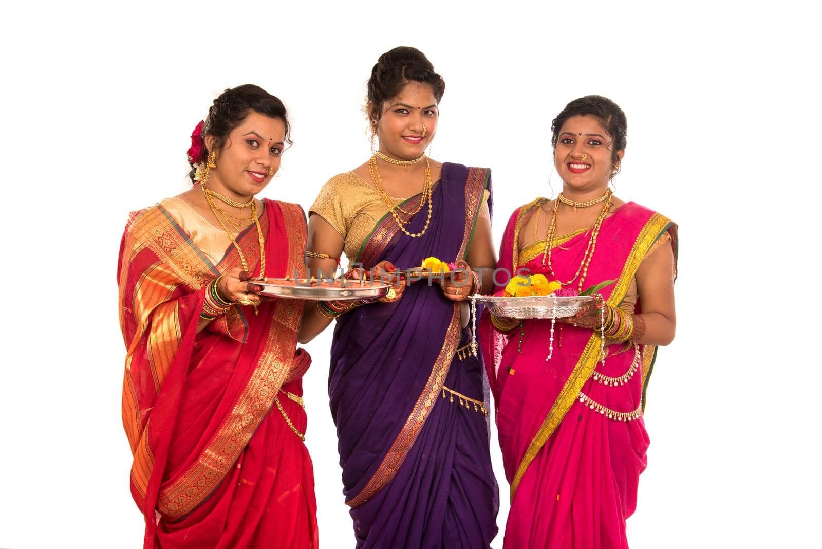 Portrait of Indian Traditional Girls holding diya and flower thali, Sisters celebrating Diwali or deepavali holding oil lamp during festival on white background