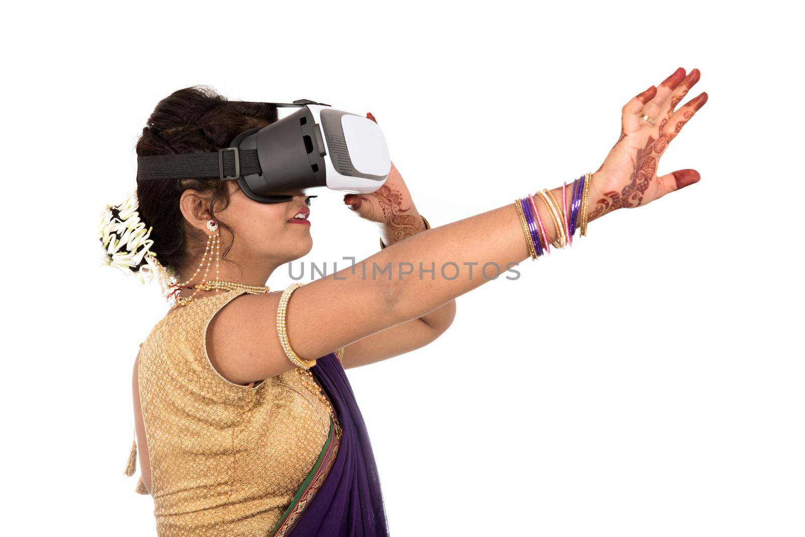 Indian traditional young woman in saree looking though VR device