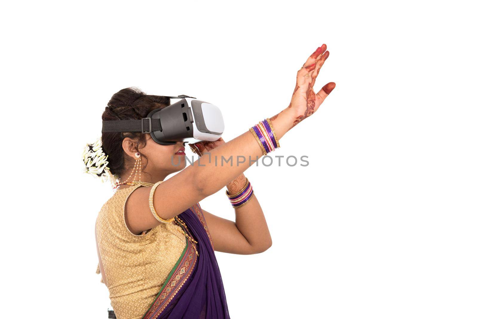 Indian traditional young woman in saree looking though VR device