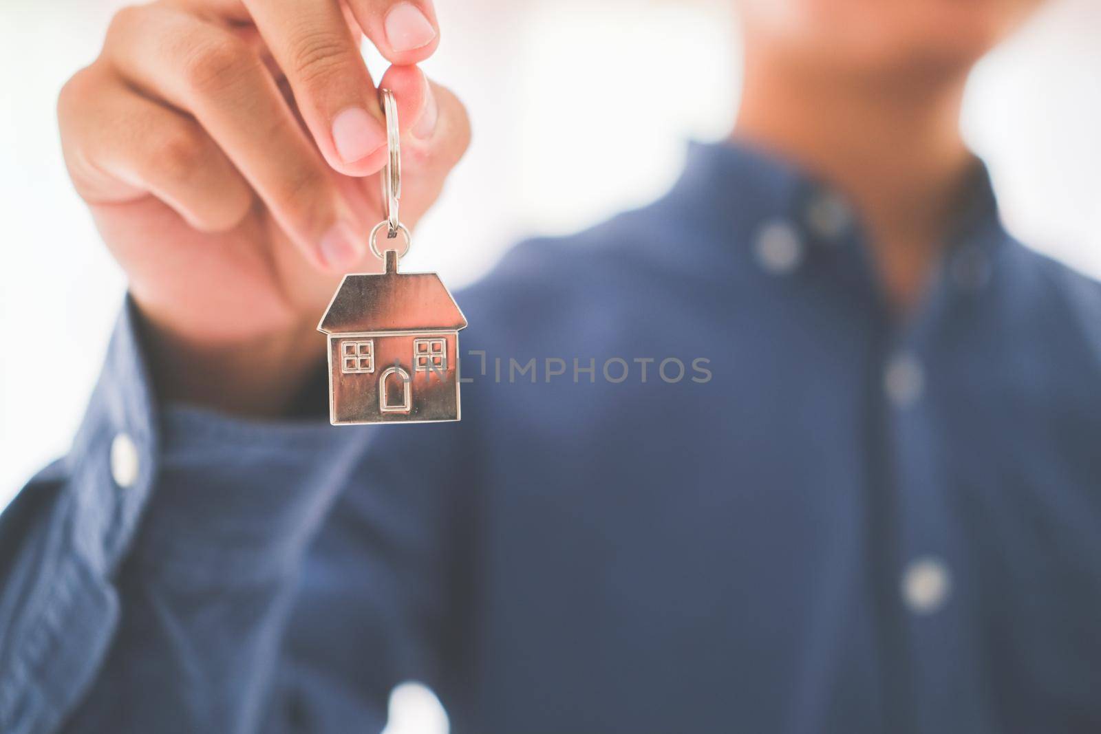 Real estate agent with house model and keys. Offer of purchase house, rental of Real Estate. Giving, offering, demonstration, holding house keys.