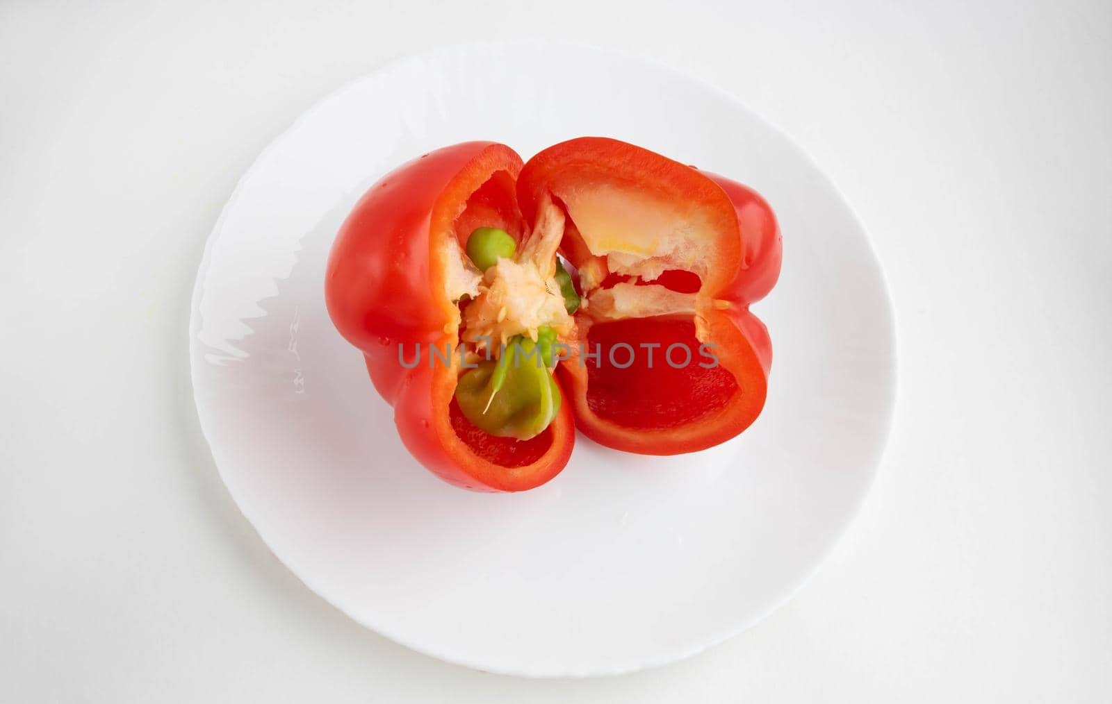 Red sliced pepper on a white plate, isolated on a white background.