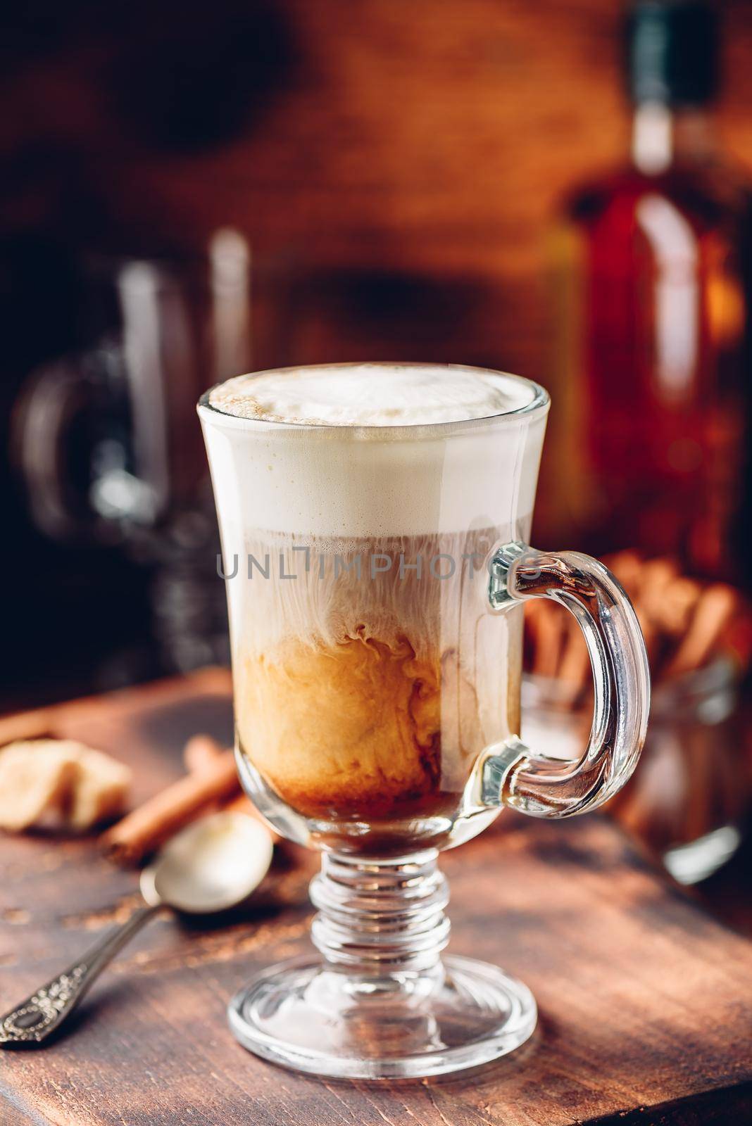 Irish coffee in drinking glass on wooden surface