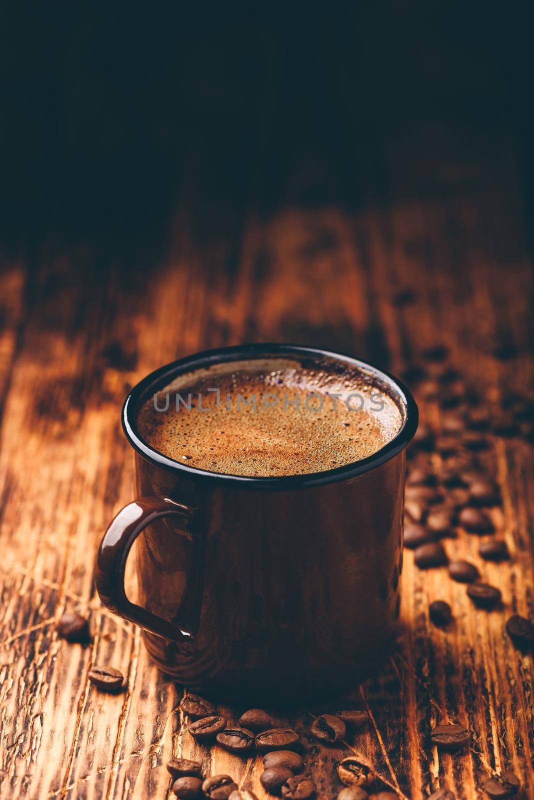 Brewed black coffee in metal mug over wooden surface