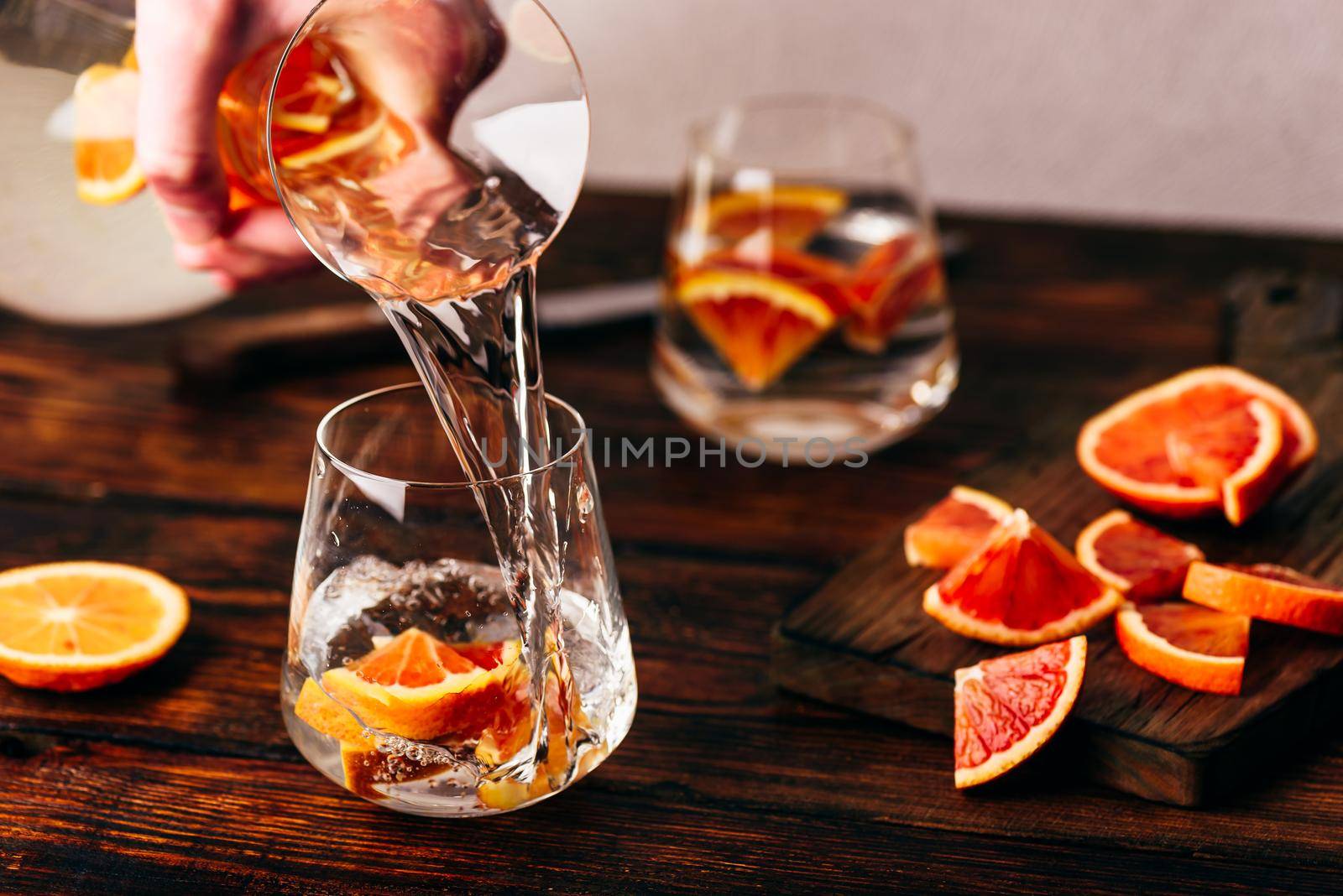 Pouring infused water with oranges into the glass by Seva_blsv