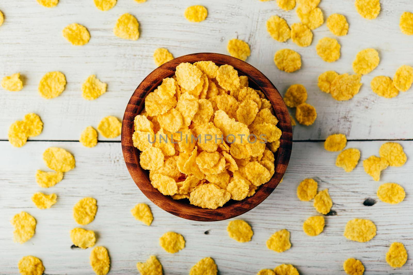 Rustic bowl of cornflakes over wooden surface. View from above