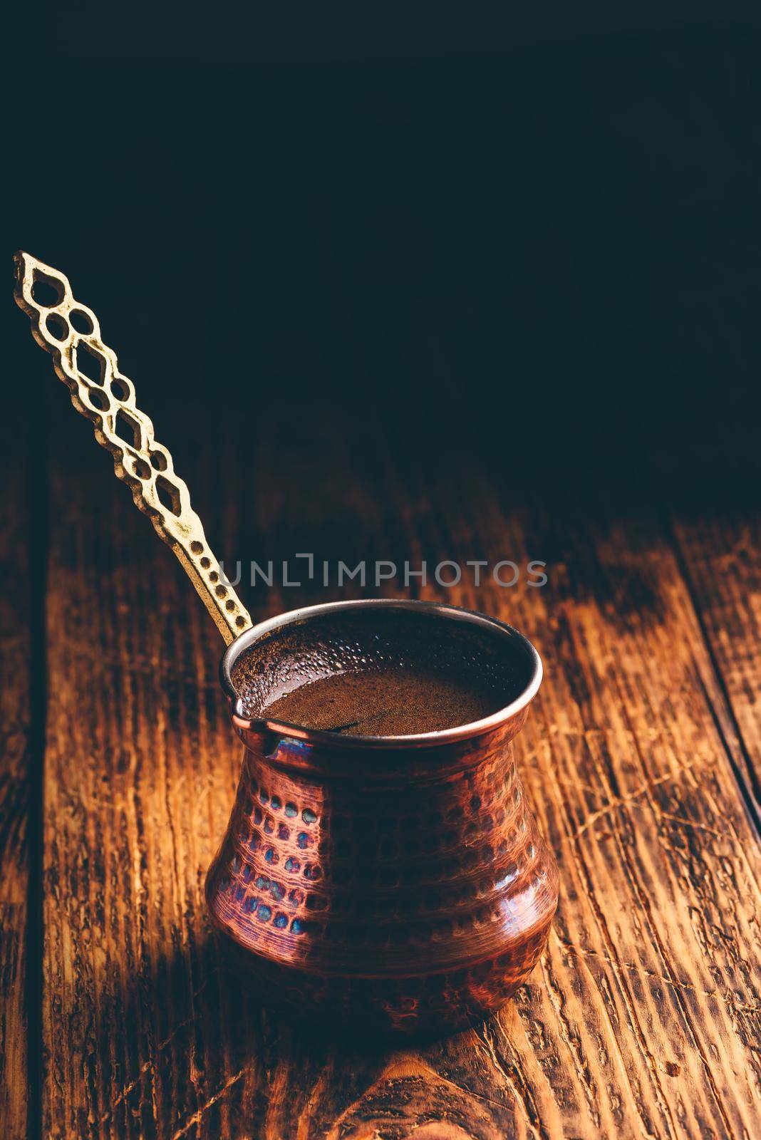 Turkish coffee. Brewed coffee in copper cezve on wooden surface