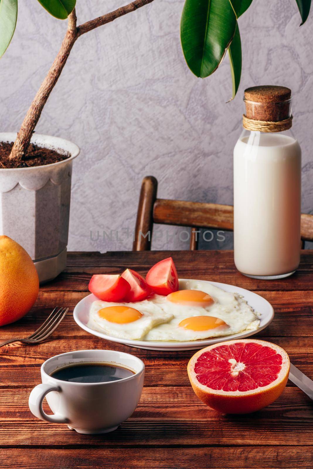 Breakfast with fried eggs, coffee, sliced tomato and grapefruit