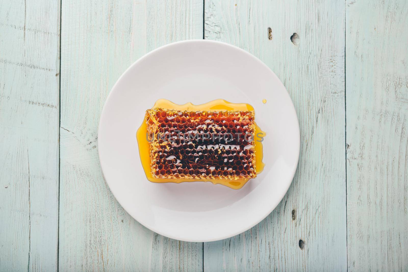 Top view of delicious yummy honeycomb on bright plate over light wooden background