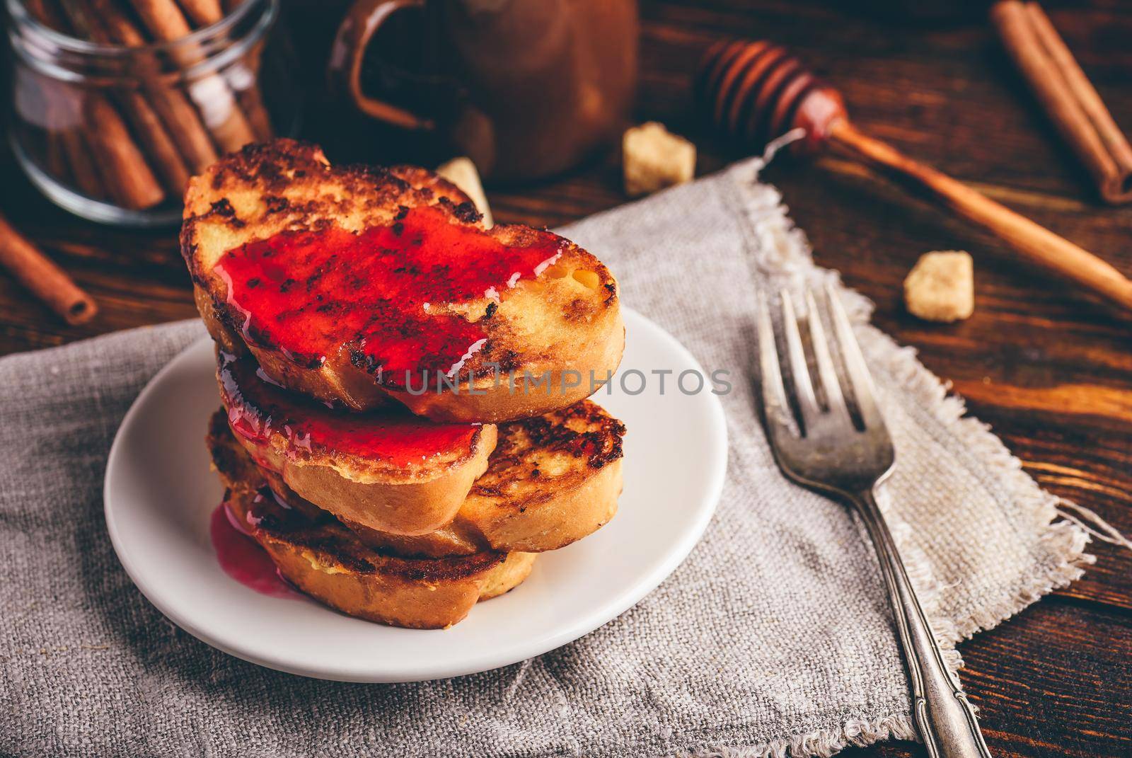 Stack of french toasts with berry marmalade on white plate