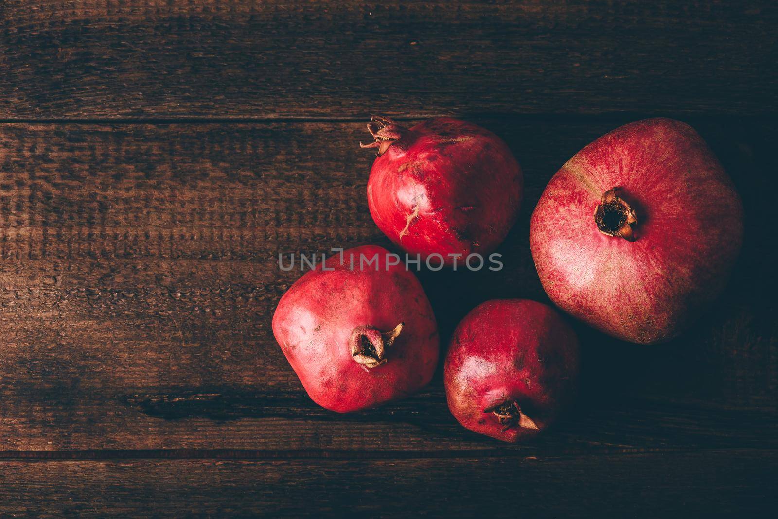 Four ripe pomegranate on rustic wooden table