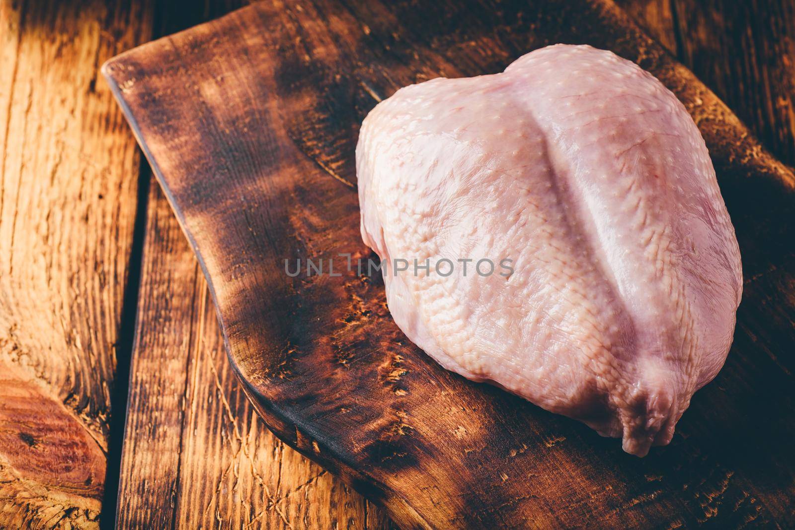 Raw chicken breast on rustic chopping board