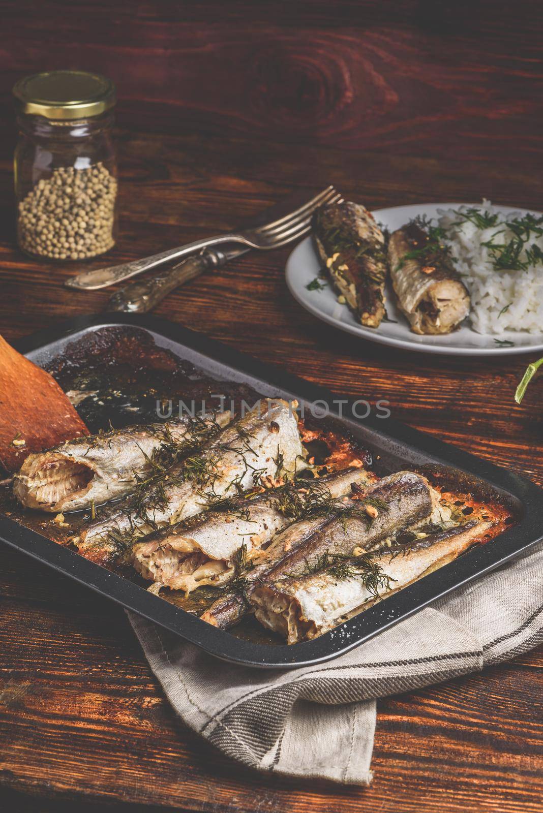 Baked fish carcasses on baking sheet over wooden surface