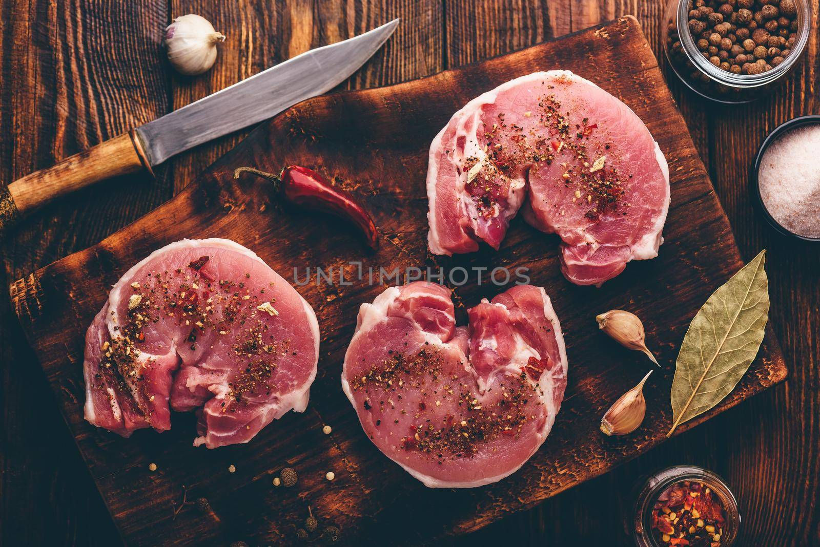 Pork loin steaks with ground spices on rustic cutting board