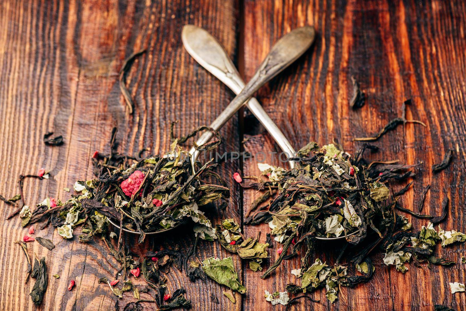 Two spoonfuls of raspberry herbal tea over wooden surface