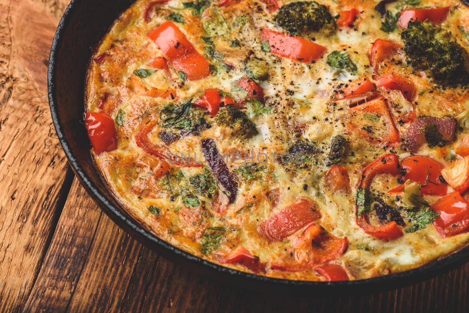 Vegetable frittata with broccoli, red bell pepper and red onion in cast iron pan