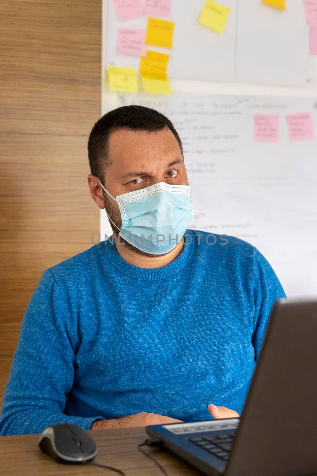 Young man with medical mask working with his laptop