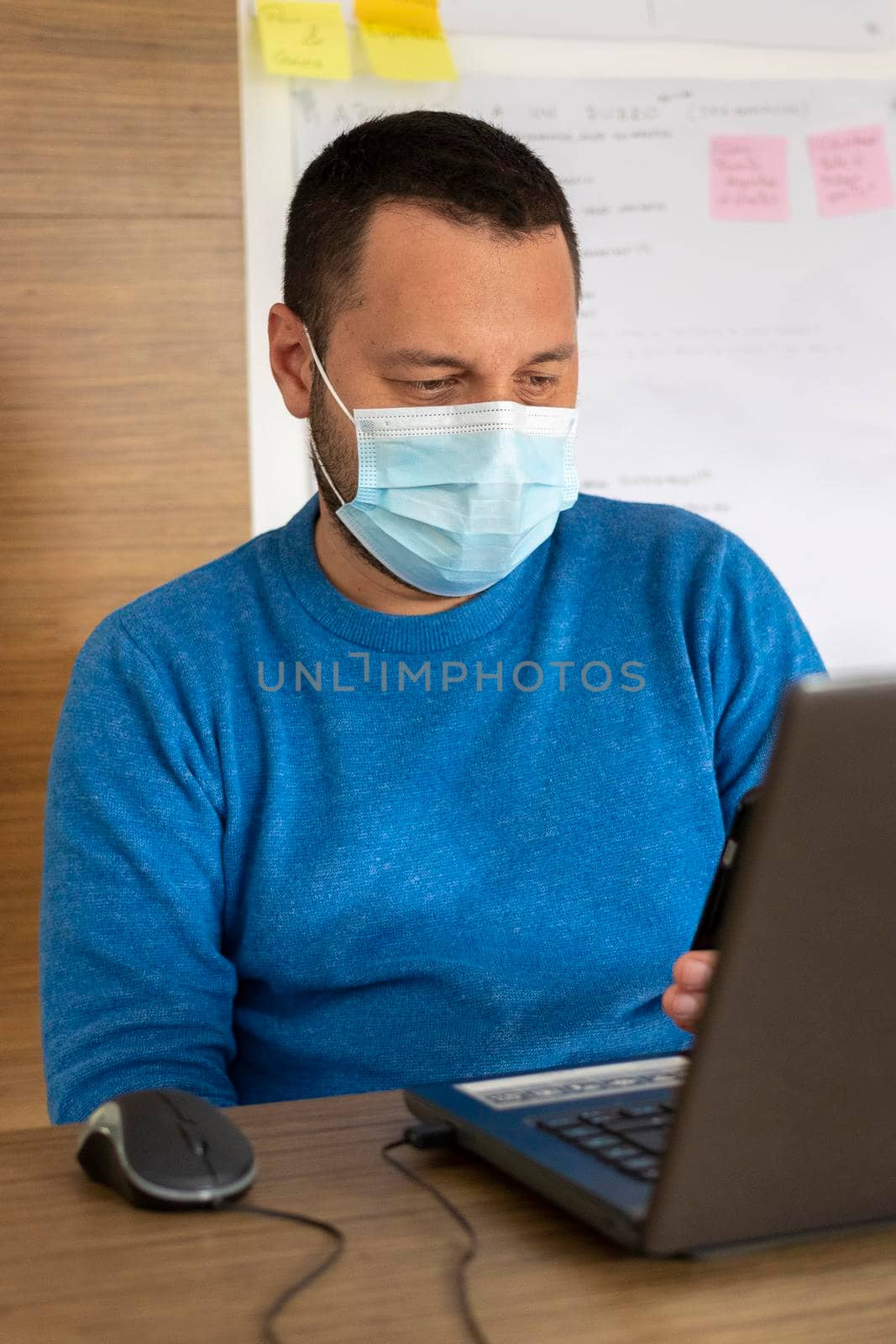 Young man with medical mask working with his laptop