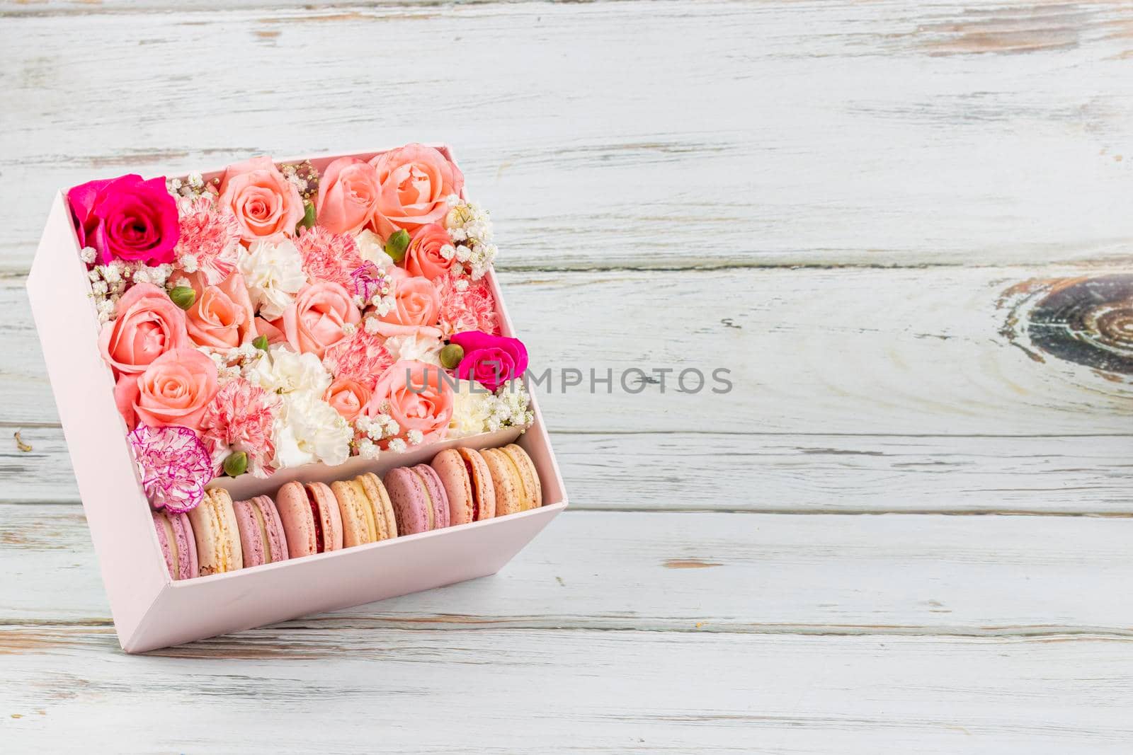 Floral arrangement of pink roses with macarons of different colors