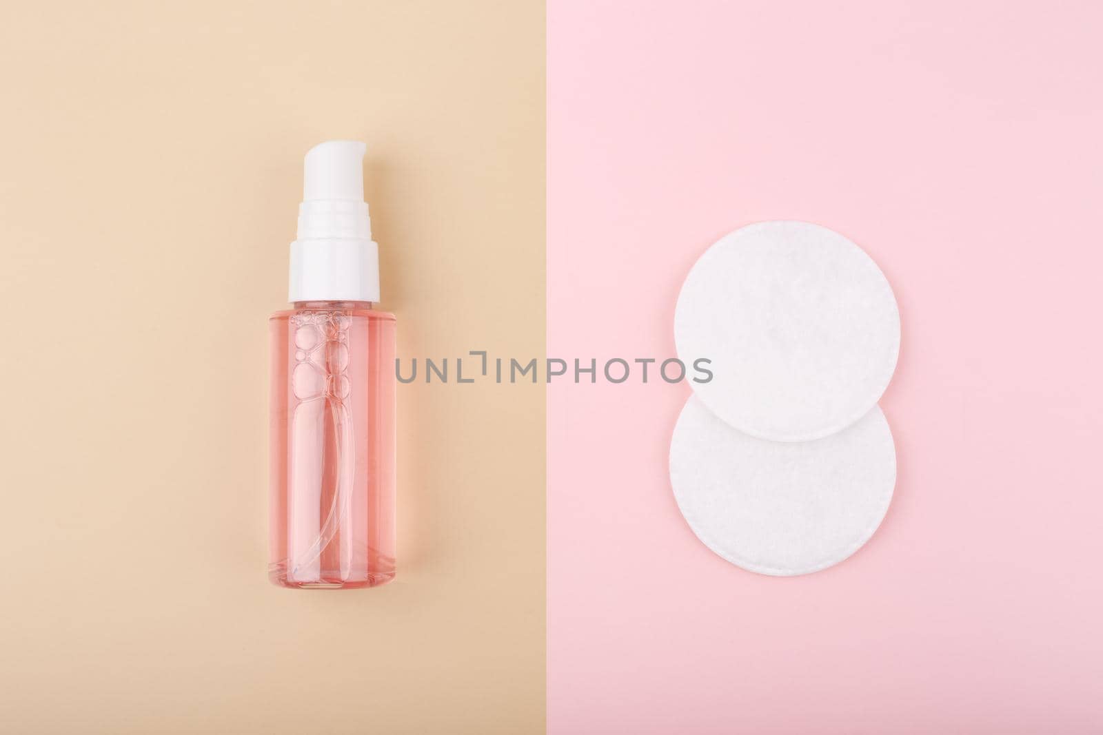 Top view of cleansing foam or gel for make up removing and cotton pads on beige and pink background. Concept of daily skin care