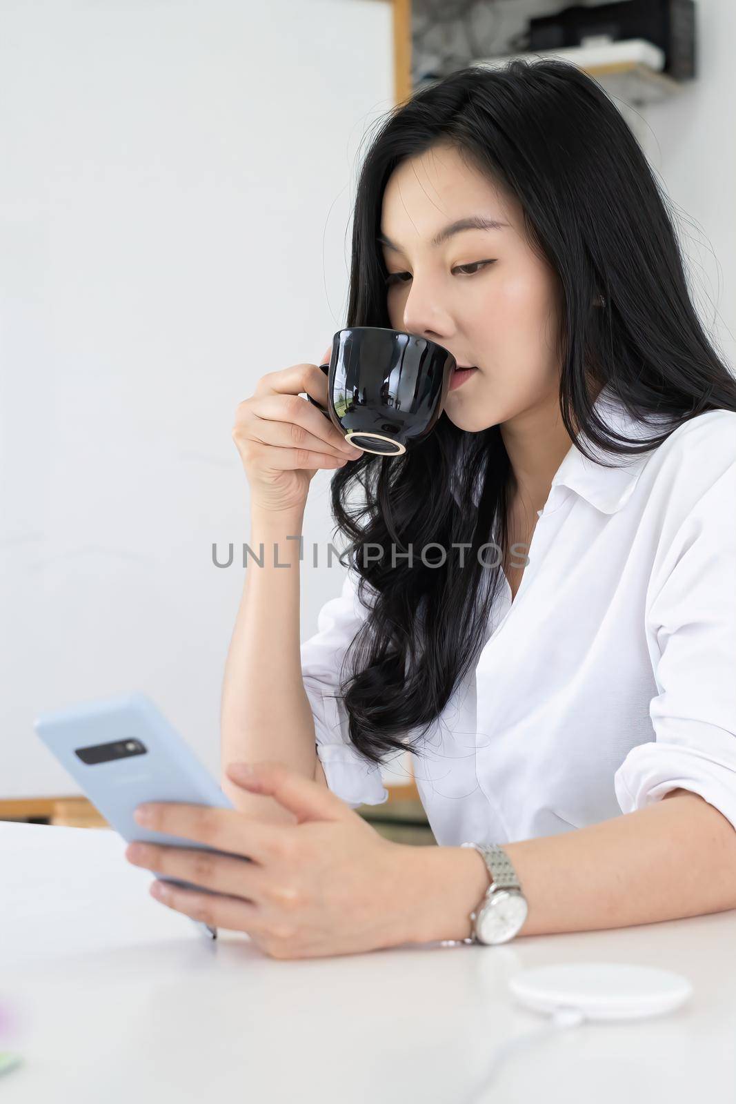 Portrait of Asian female business financial checking her port stock market in mobile application at morning with coffee. by itchaznong
