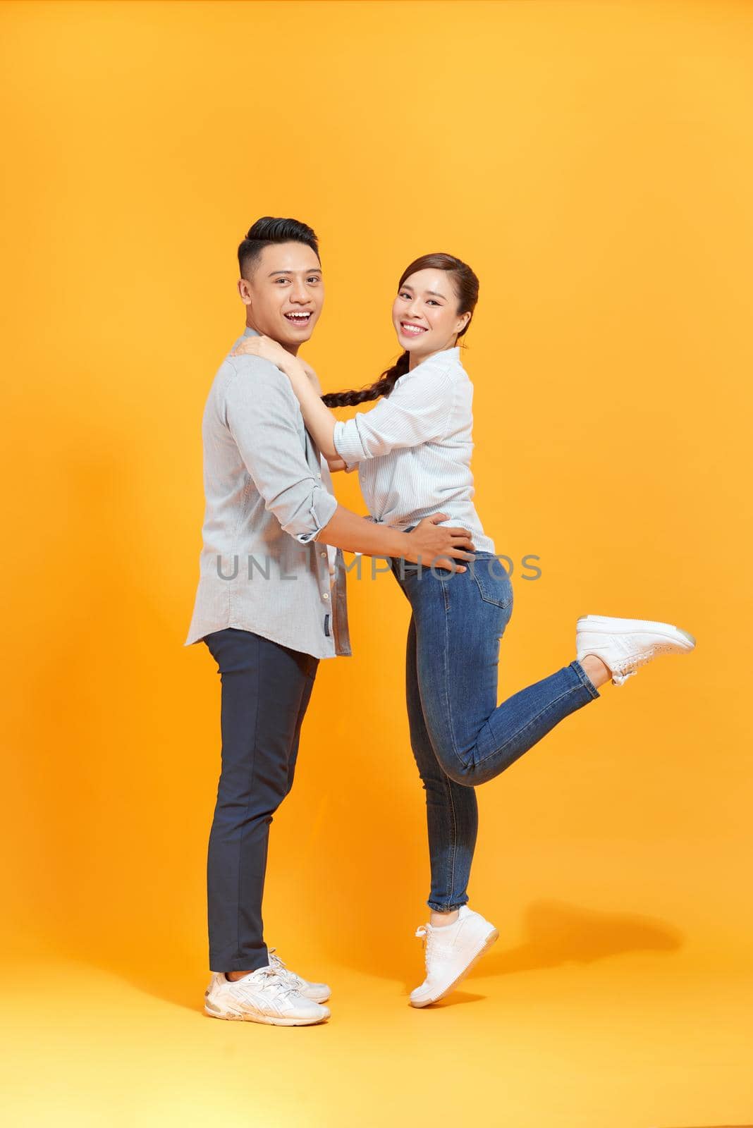 Cute couple, guy holding carrying lady lovely  moment isolated yellow color background