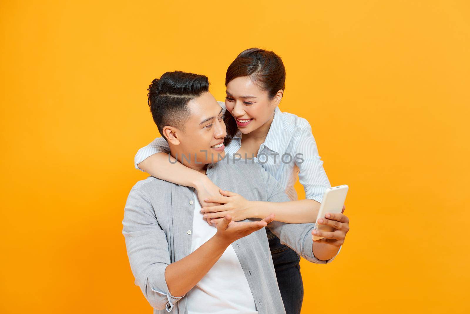 Funny couple or marriage sharing a smart phone to watch media content