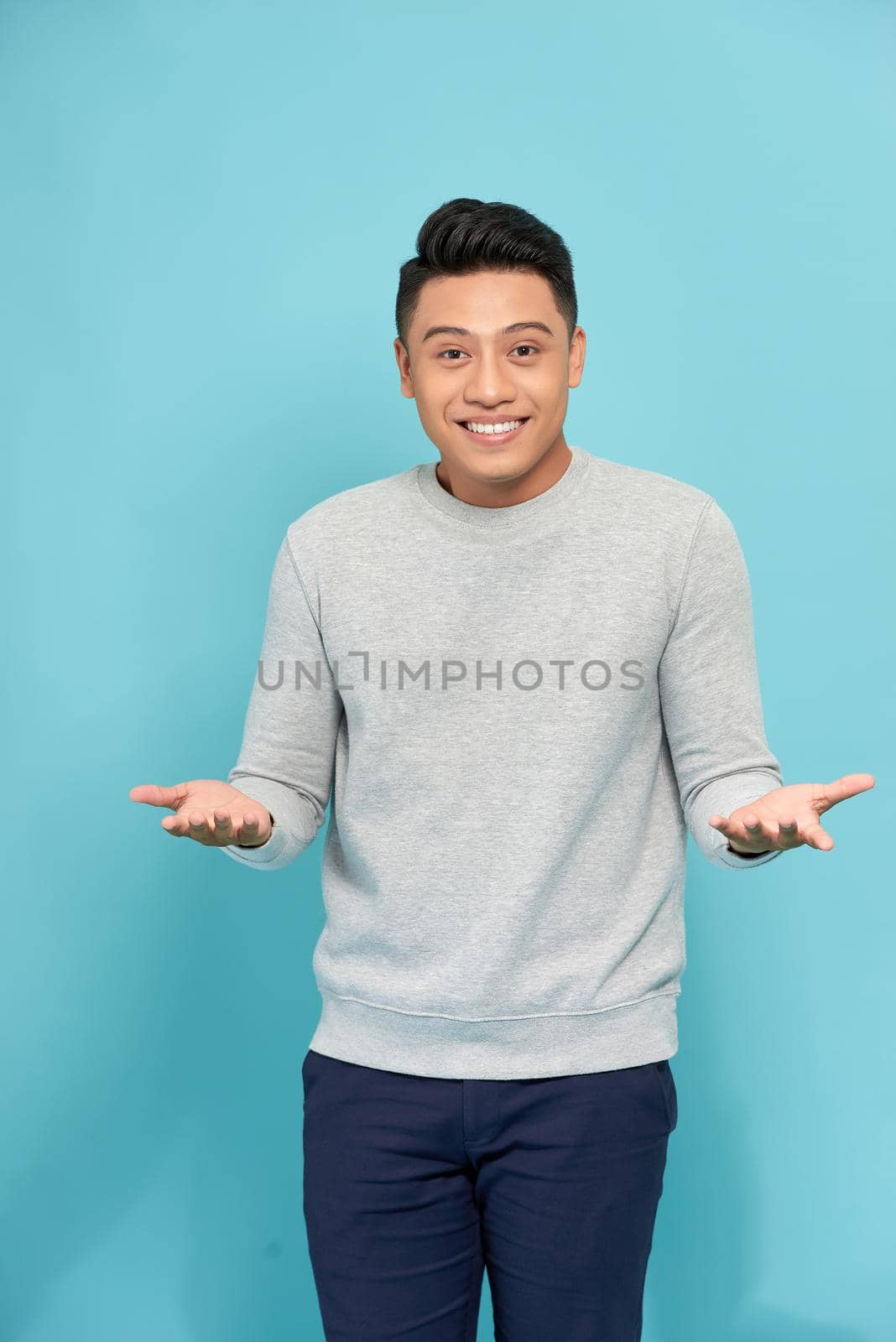 Young happy handsome Asian man raising his hands with open palms gesture