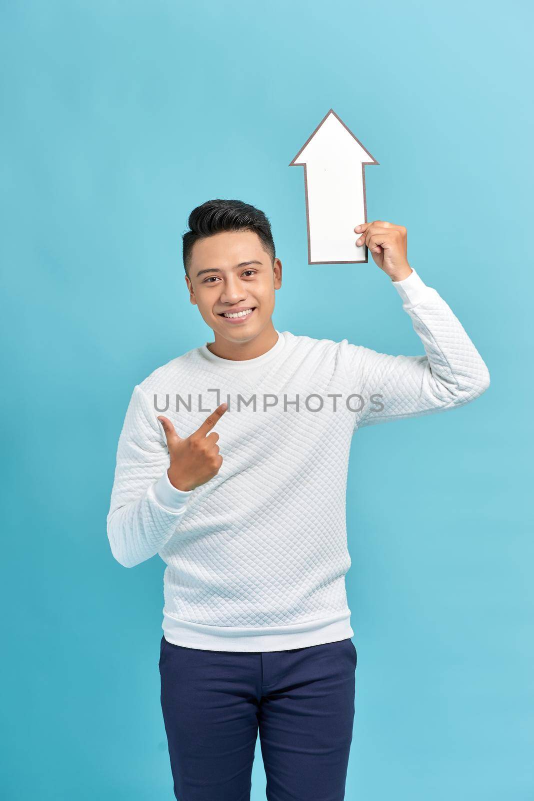 young man raises white arrow isolated on blue