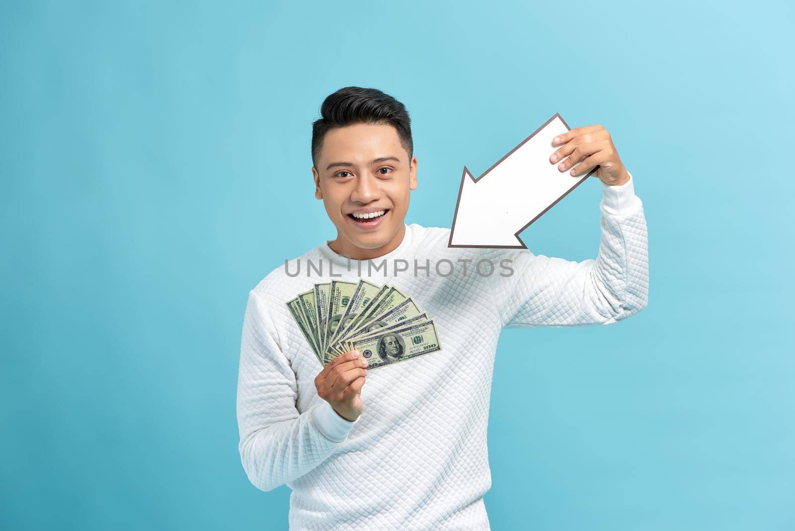 Man holding money and white arrow over blue background