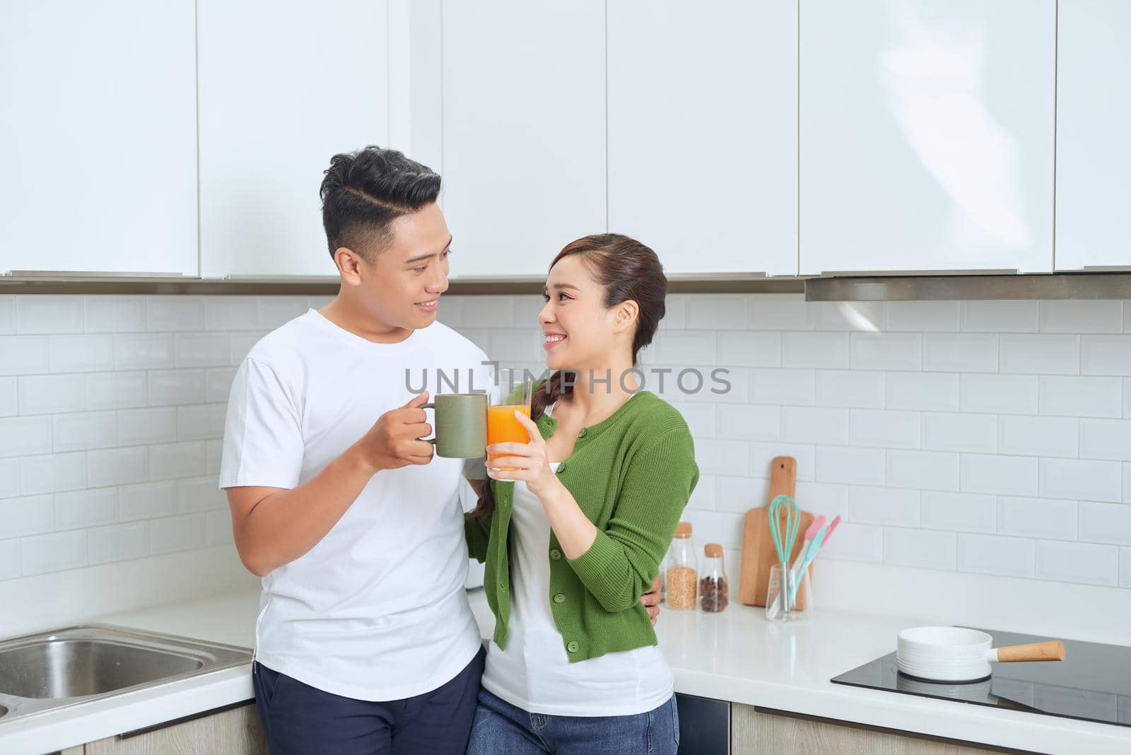 happy young couple standing in the kitchen in their house. by makidotvn