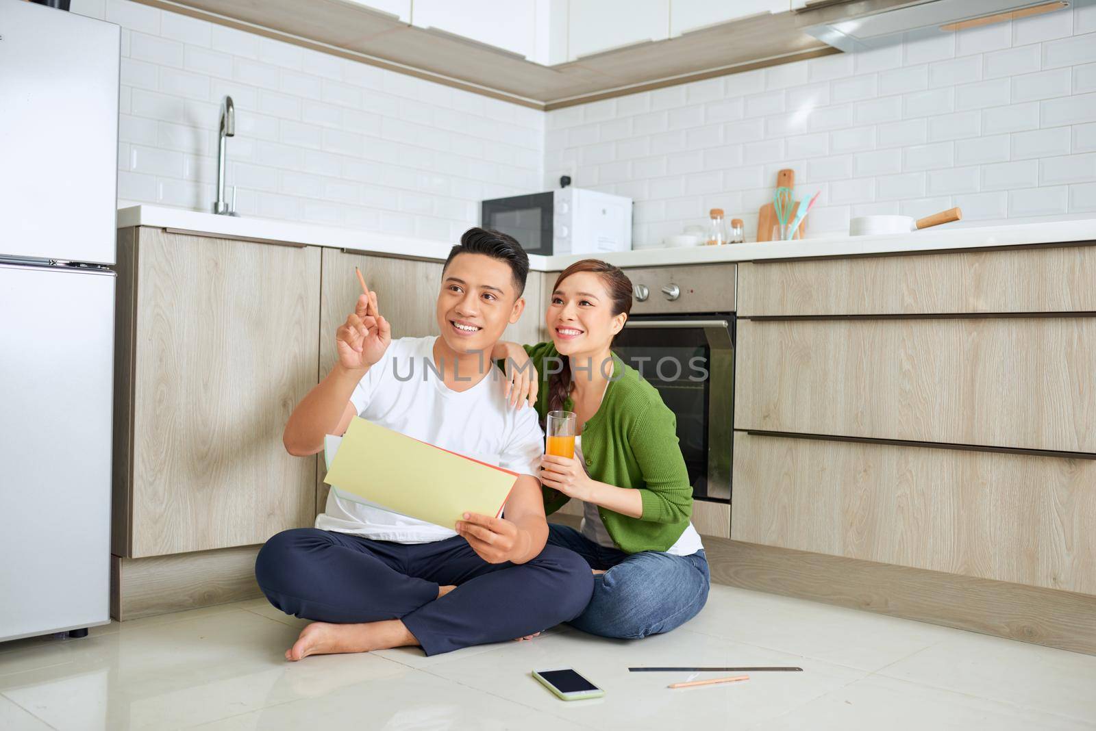 Man and woman looking at their house plans sitting in their new house by makidotvn