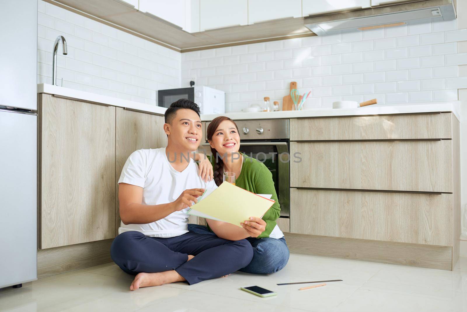 Man and woman looking at their house plans sitting in their new house by makidotvn