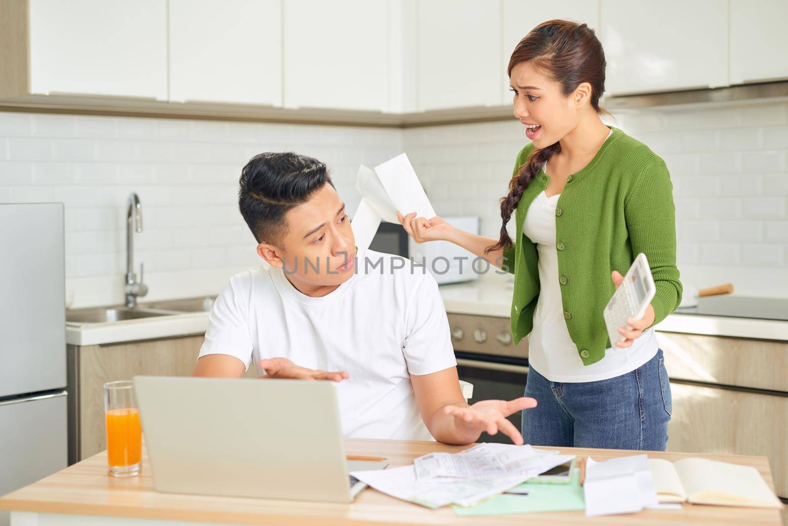 Angry young couple arguing by their many debts at home. Financial family problems concept.