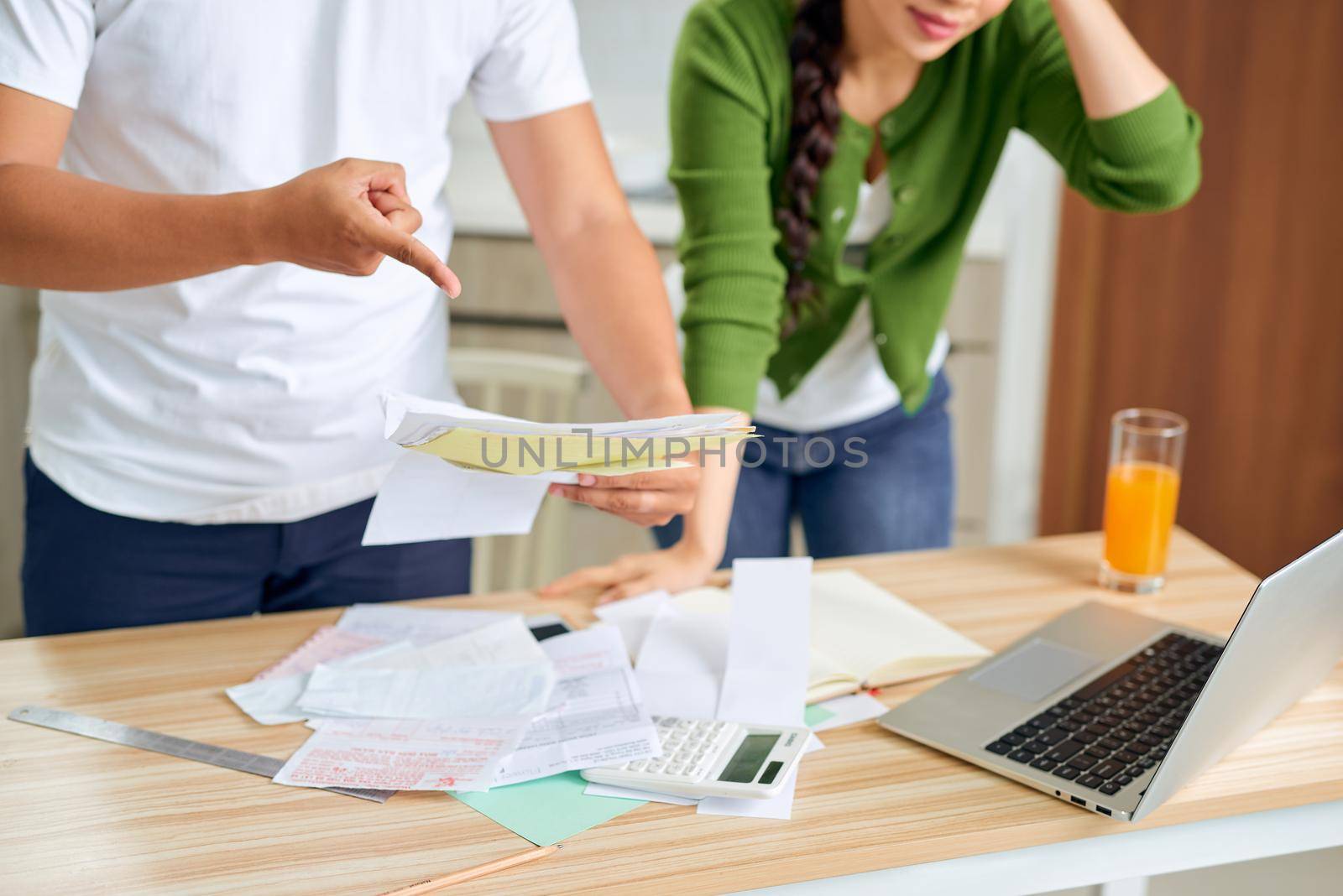 Angry young couple arguing by their many debts at home. Financial family problems concept.