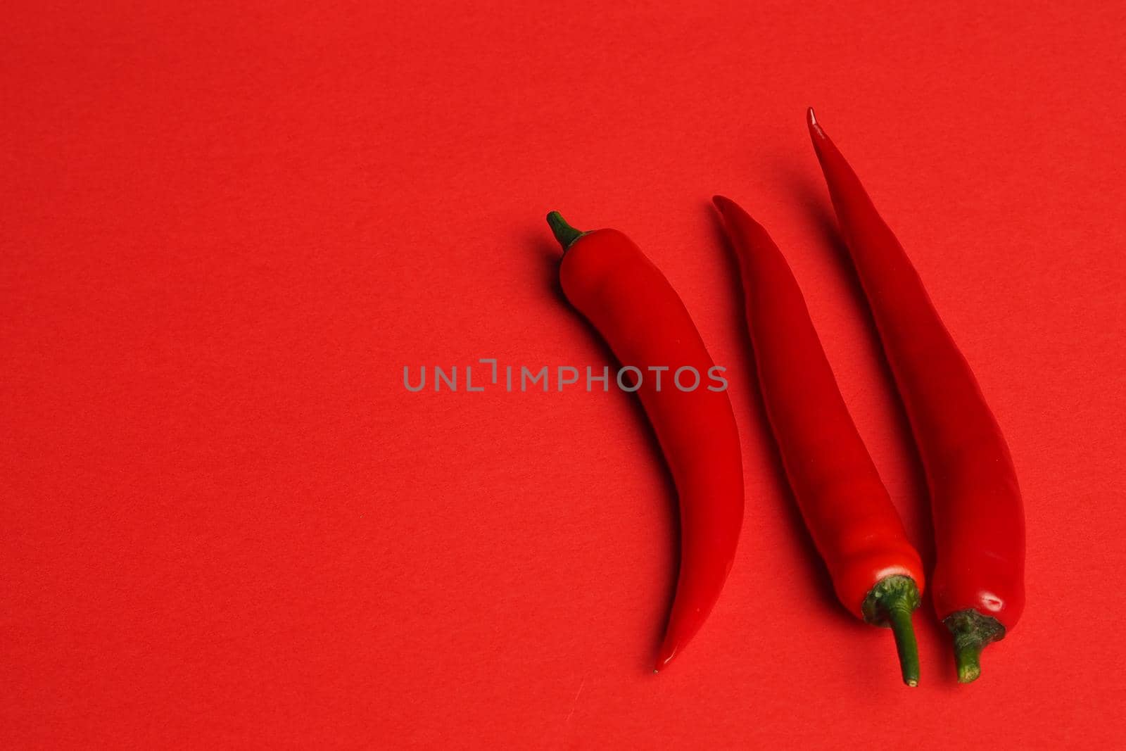 Vegetables and food. Red pepper chili spicy isolated on a red background. High quality photo