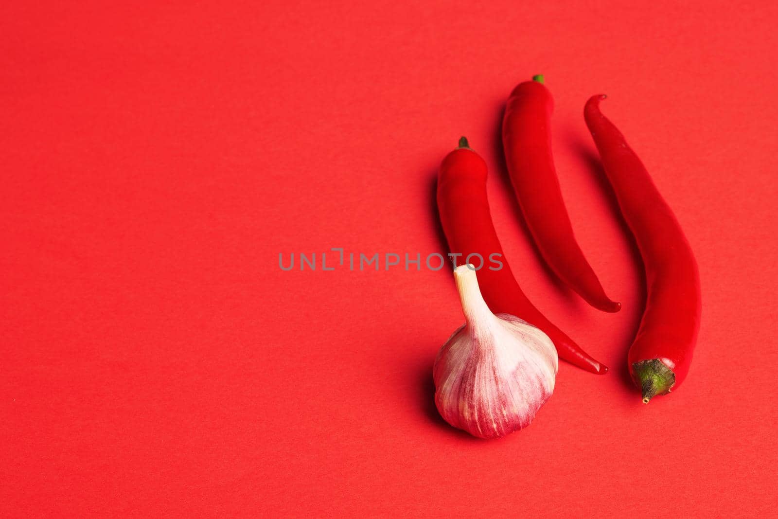 Red pepper and garlic. Food, ripe vegetables and spices, close-up, isolated, red background, with a place to label. High quality photo