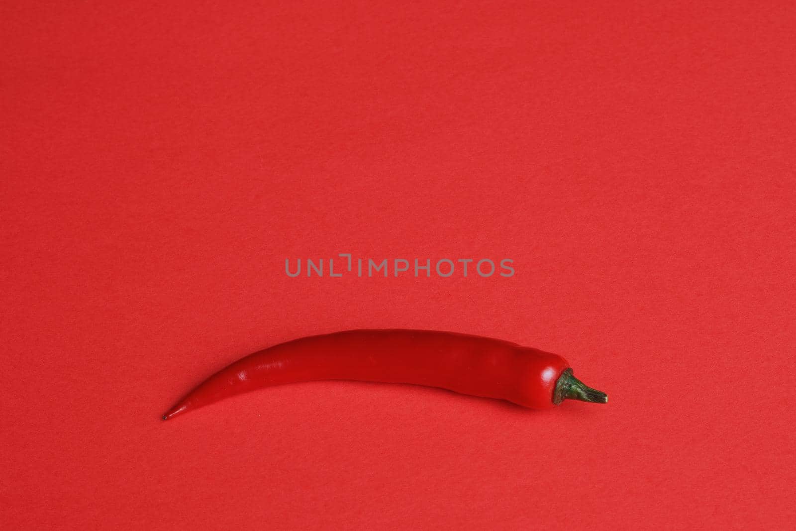 Vegetables and food. Red pepper chili spicy isolated on a red background. by Olga26