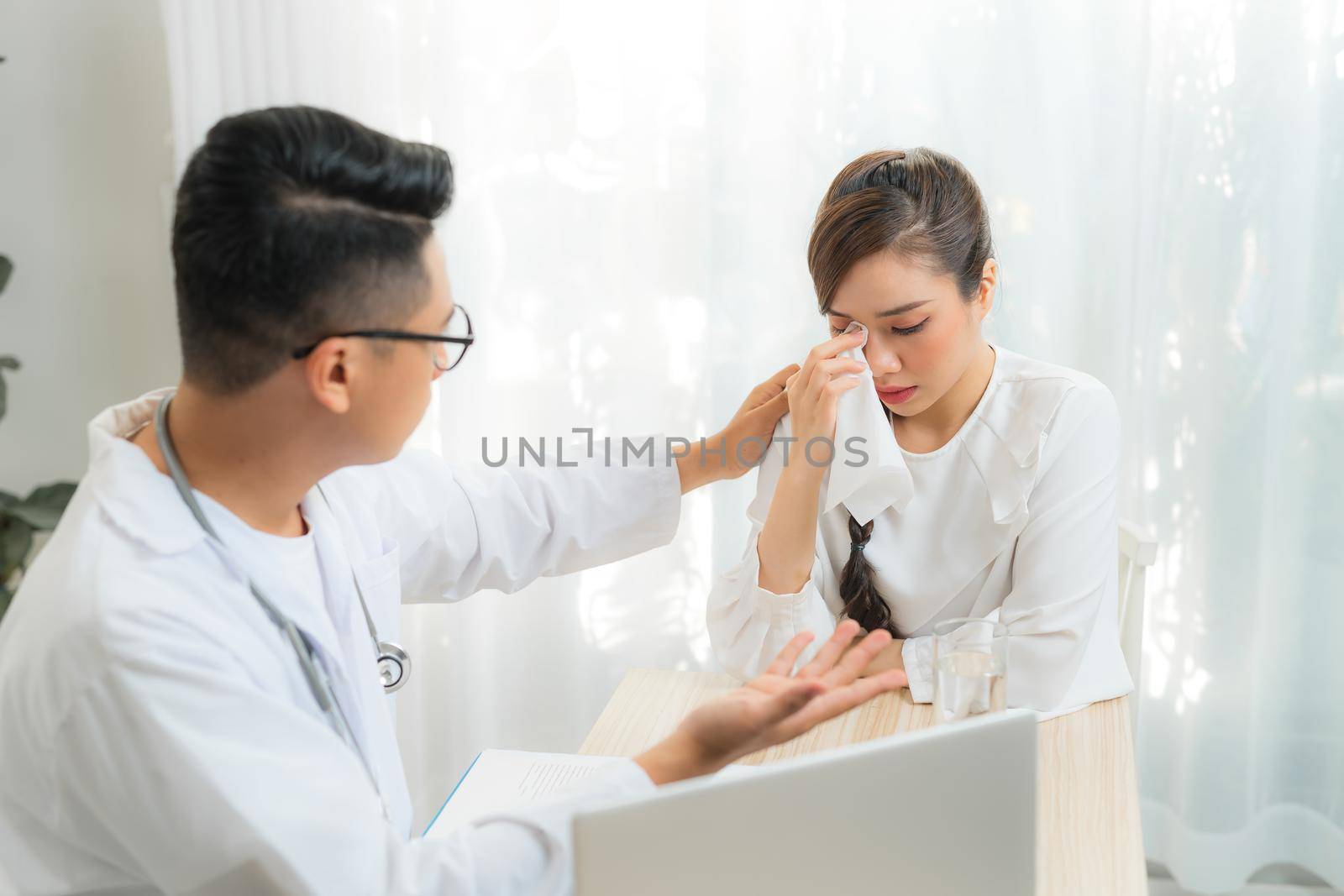 Young male Obstetrician-gynecologist consulting with patient in clinic or hospital. by makidotvn