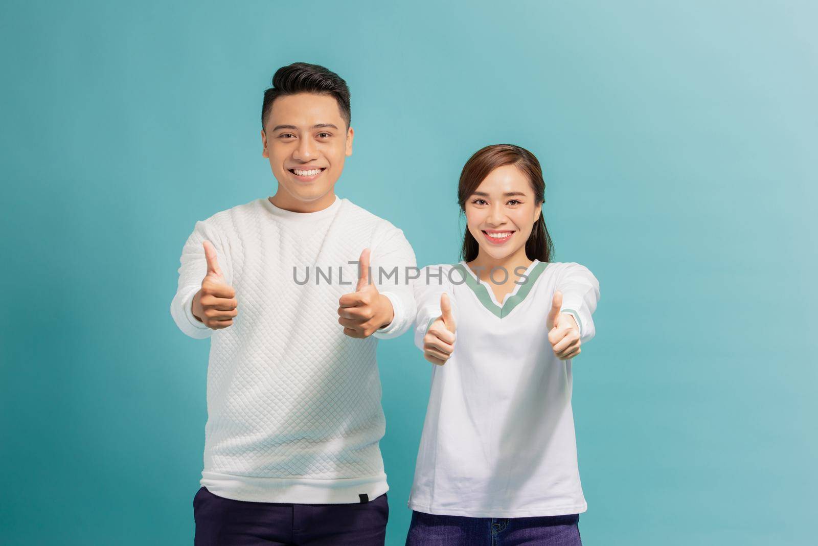 Attractive cheerful young lovers showing thumbs up