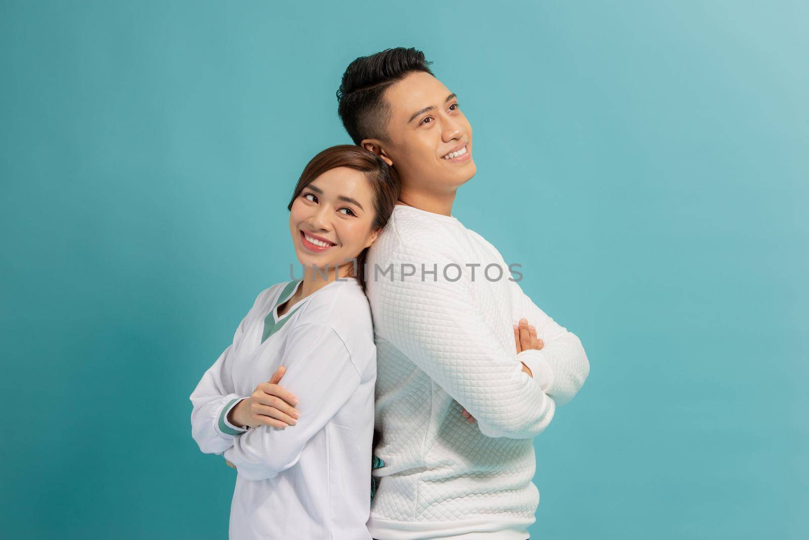 Happy loving couple. Studio shot of beautiful young couplestanding back to back and smiling