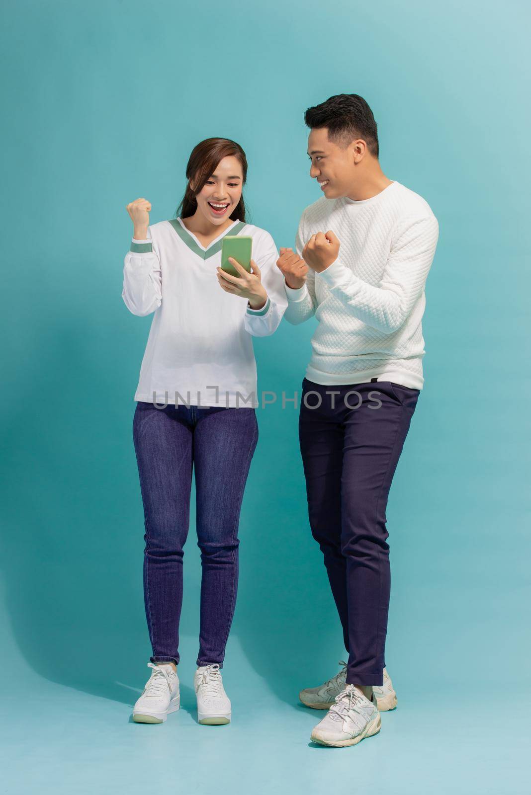 surprised Asian couple watching the smartphone by makidotvn