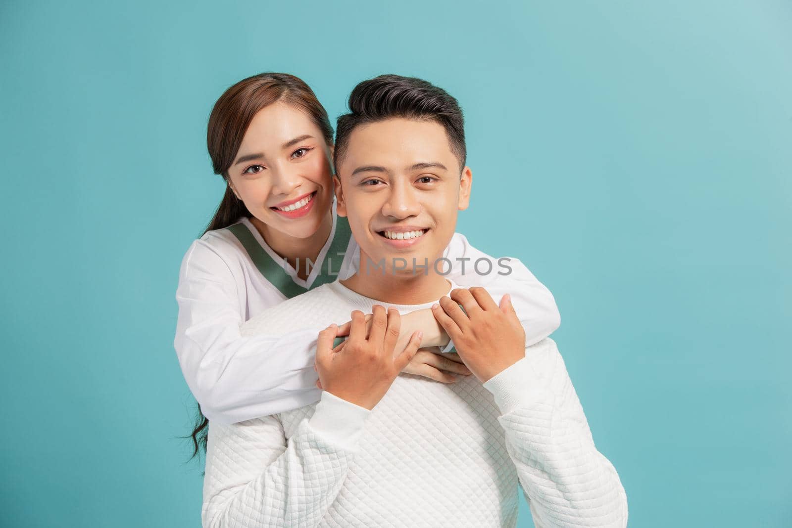 Happy couple embracing and looking camera on blue background