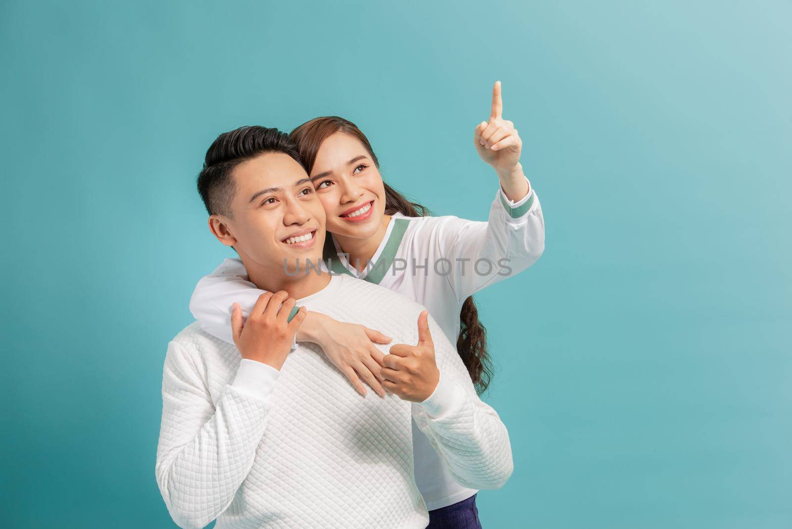 beautiful young happy couple love smiling embracing point finger to empty copy space, man and woman smile looking up,